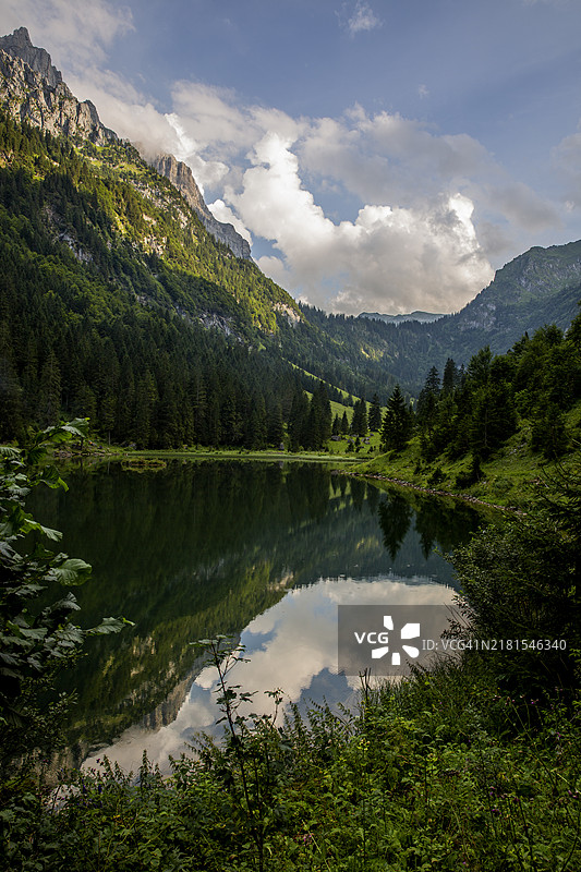 瑞士高山湖泊中绿山和多云天空的完美倒影图片素材