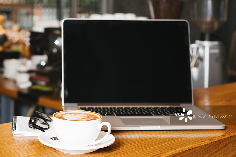 笔记本电脑咖啡木质表面正面图图片素材