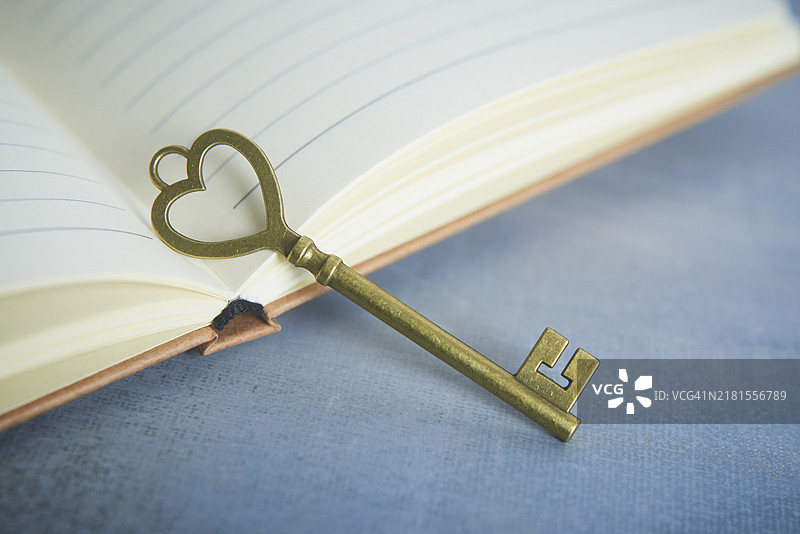 古董心形钥匙静静放在打开的笔记本上图片素材