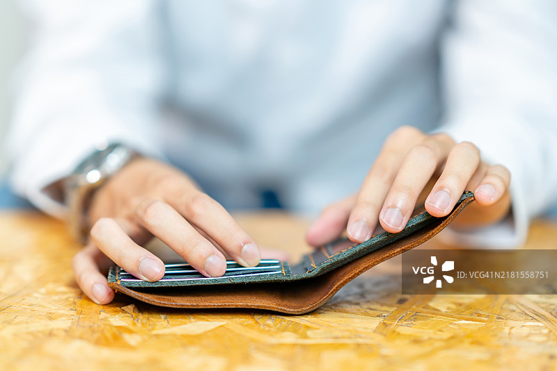 特写镜头：男人从钱包中拿出信用卡准备付款图片素材