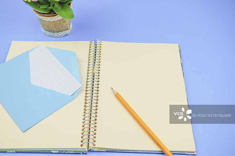 蓝色信封和信件的空白笔记本上的铅笔图片素材