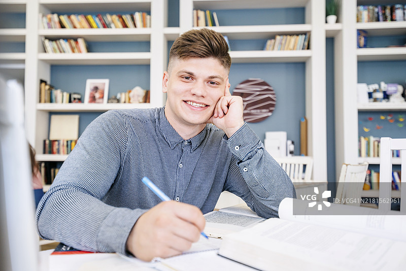 坐在图书馆里看书写字的学生图片素材