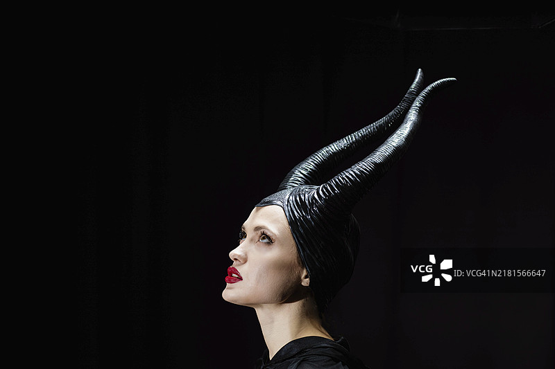 带恶魔角的梦幻女巫，万圣节服装。黑色背景上美丽的黑色魔法神秘女性图片素材