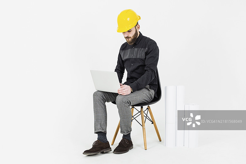 戴黄色安全帽的土木工程师使用笔记本电脑图片素材