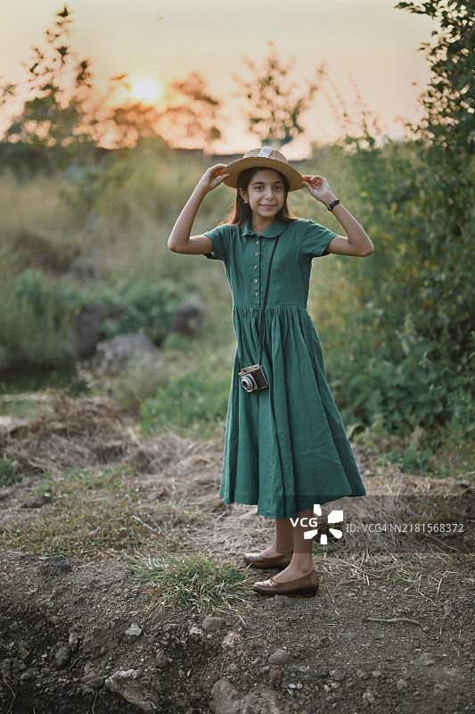 穿着经典绿色亚麻裙和草帽的女孩在夕阳下图片素材