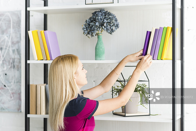 女人在家里的书架上选书图片素材