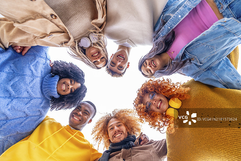 多民族人群围成一圈，微笑看向镜头（仰视角度）图片素材