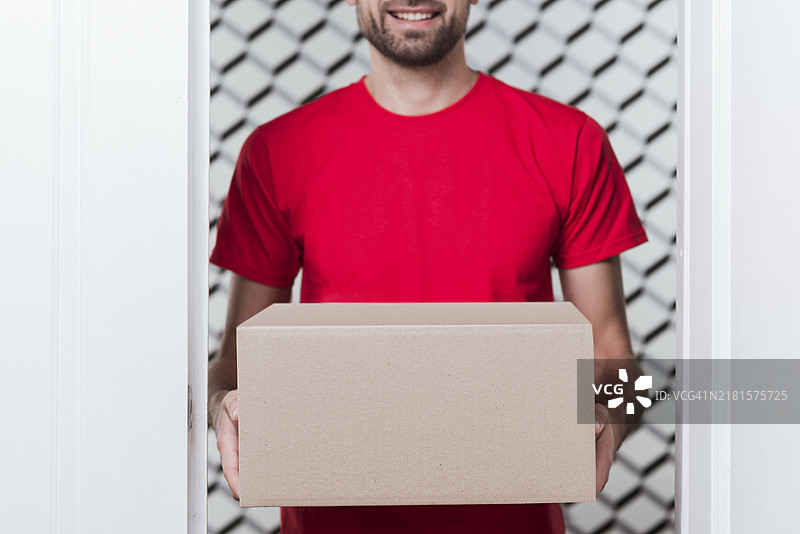 穿着红色制服的送货员的盒子特写正面图图片素材