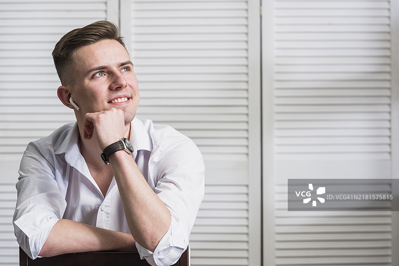 戴着无线耳机、面带微笑看向远方的年轻男子图片素材