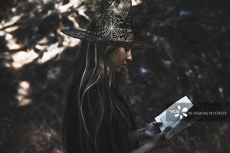 穿着女巫服装的女士在读书图片素材
