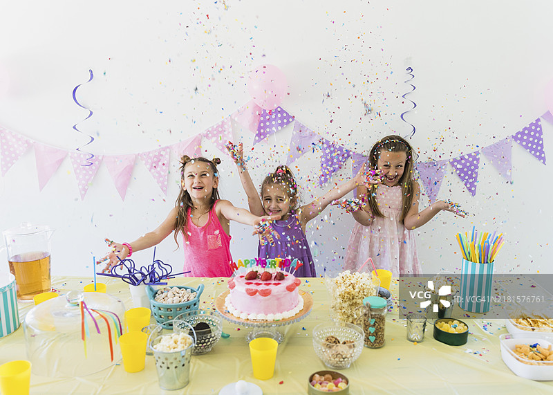 漂亮女孩们在家享受生日派对，桌上摆满各种食物和果汁图片素材
