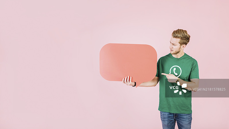 男人指着粉红色背景上的空白橙色对话气泡图片素材