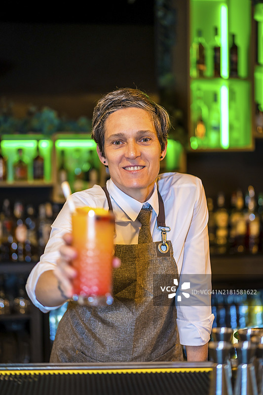 快乐的调酒师在酒吧柜台调制豪华鸡尾酒竖版肖像图片素材