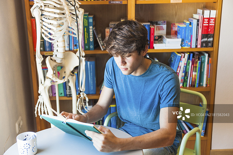 青少年男孩在图书馆的桌子上看书图片素材