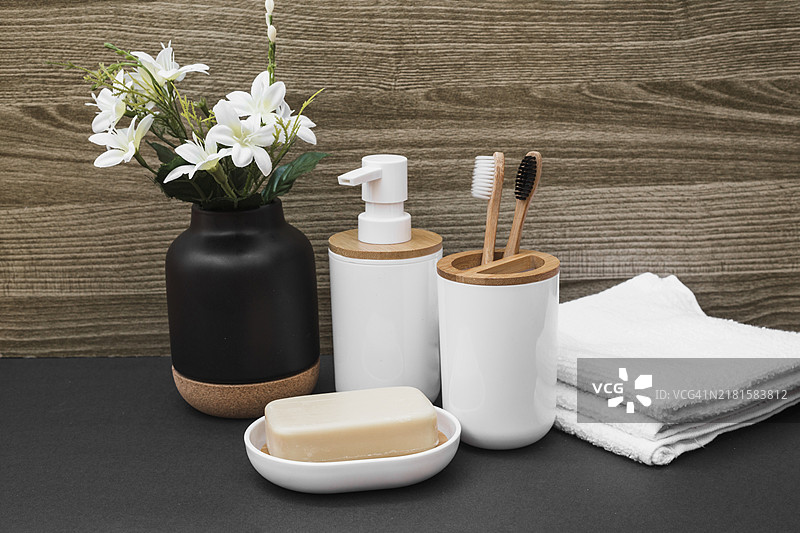 香皂牙刷化妆品瓶毛巾白色花瓶黑色表面图片素材