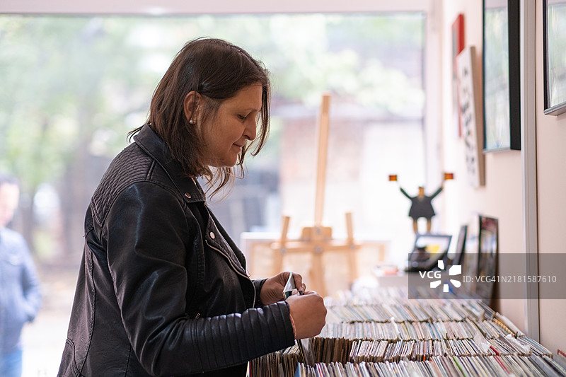 唱片商店：身穿黑色皮夹克的女子在唱片店内图片素材