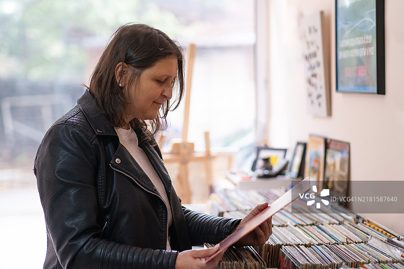 唱片店。一位穿着黑色皮夹克的女性在唱片店里。图片素材