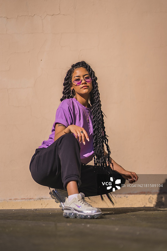 都市风情：佩戴紫色眼镜的年轻深色皮肤辫发女子图片素材