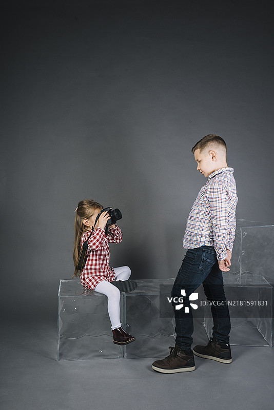 女孩与带相机的男孩，灰色背景图片素材
