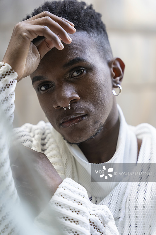 穿着白色现代西装和黑色皮靴的非洲裔年轻男子，城市街道上的时尚模特图片素材