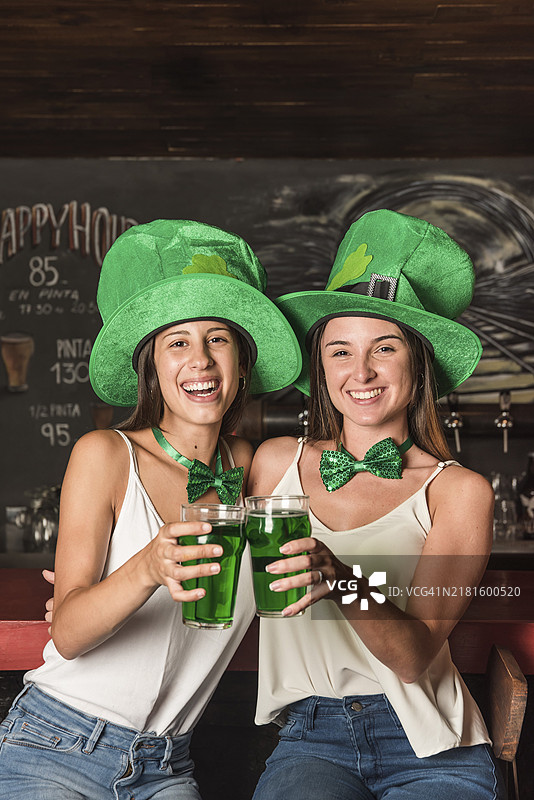 戴着圣帕特里克帽，在酒吧喝酒庆祝的年轻女子图片素材