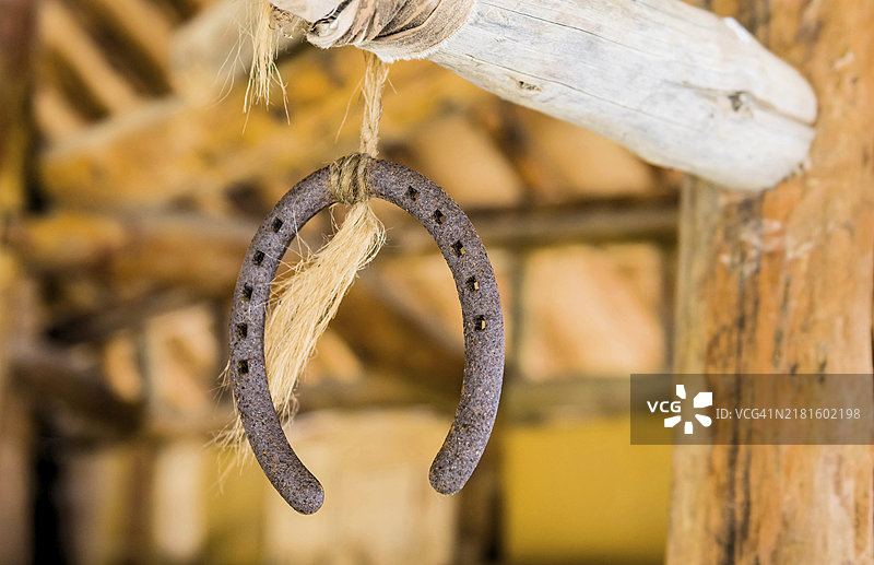粗绳悬挂在木杆上的生锈马蹄铁图片素材
