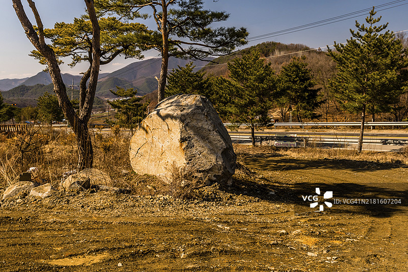 韩国乡村道路旁树荫下的大花岗岩巨石图片素材