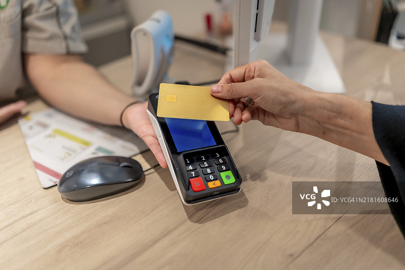 药房内顾客使用非接触式信用卡支付特写图片素材