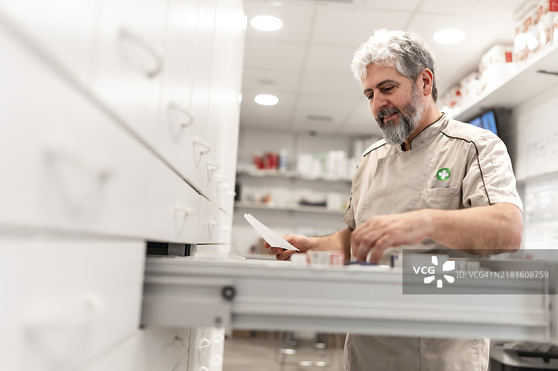 现代药房的仓库里，一位自信的中年男药剂师正在工作图片素材