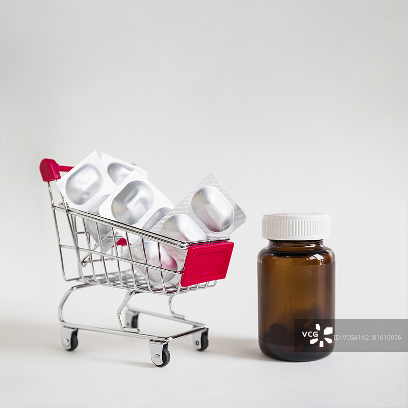 白色背景上的药丸泡罩购物车和玻璃瓶图片素材
