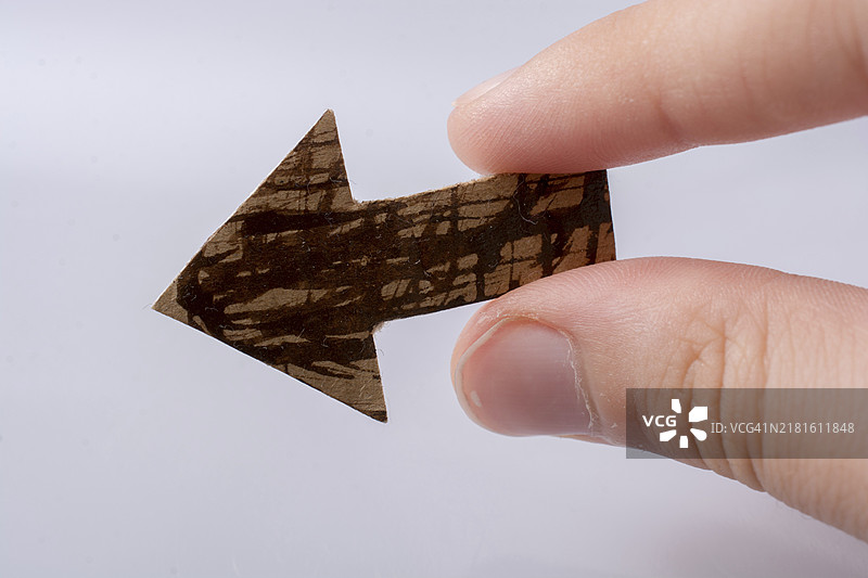 手持棕色纸质箭头图片素材