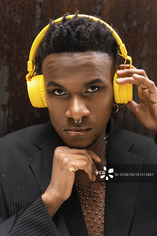 戴着黄色无线耳机听音乐并看着镜头的黑人男子肖像图片素材