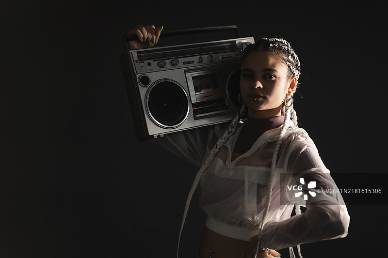 肩扛音响、梳着白色辫子的年轻女孩肖像（竖版照片）图片素材