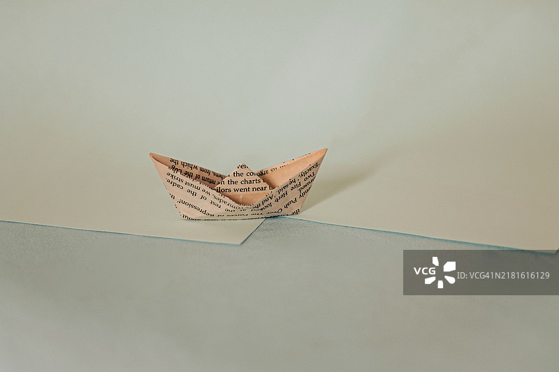 蓝色调对角分割背景上的简单折纸船图片素材