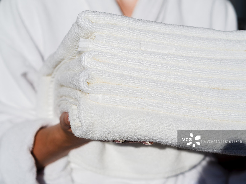 女人手持白色折叠干净的毛巾图片素材