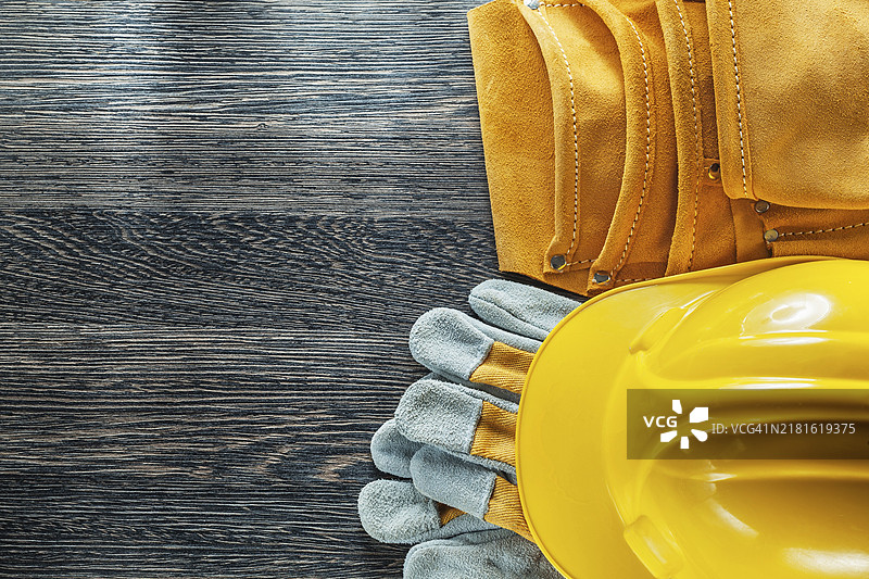 木板上的皮革工具腰带、建筑头盔和防护手套图片素材