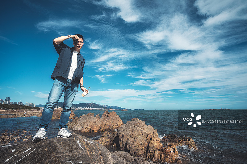 青岛，山东省，一名男子在海滩上使用相机的照片图片素材