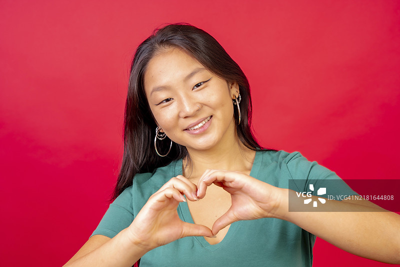 中国女人用手象征心形的红色背景影棚照片图片素材