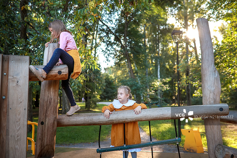 在公园的木质环保游乐场上玩耍的唐氏综合症女孩图片素材