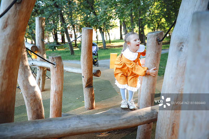 一个9岁患有唐氏综合症的顽皮孩子在阳光明媚的日子里享受环保公园的游乐场图片素材