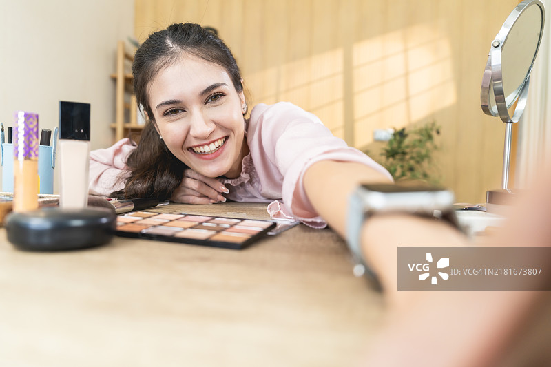 在家中书桌前享受化妆的微笑女人图片素材