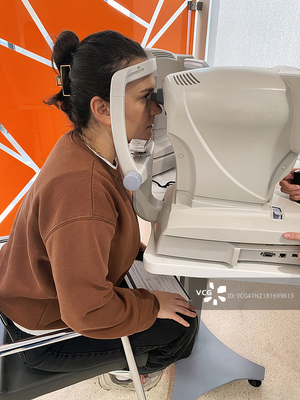 年轻女人在诊所使用自动化设备进行眼科检查图片素材