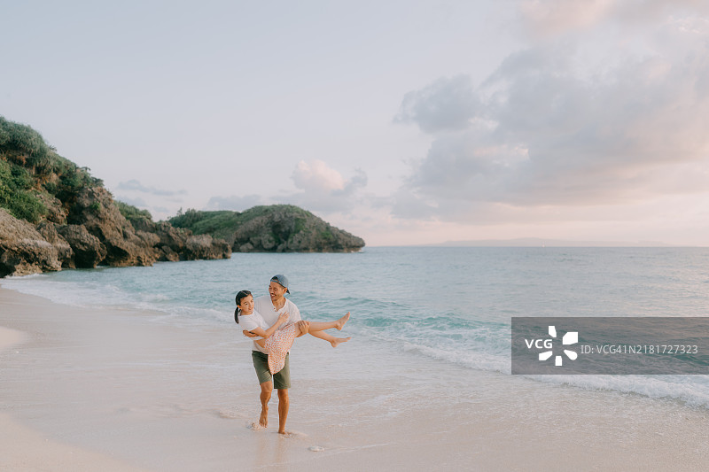 父亲和小女儿在日落时分的海滩上玩得很开心图片素材