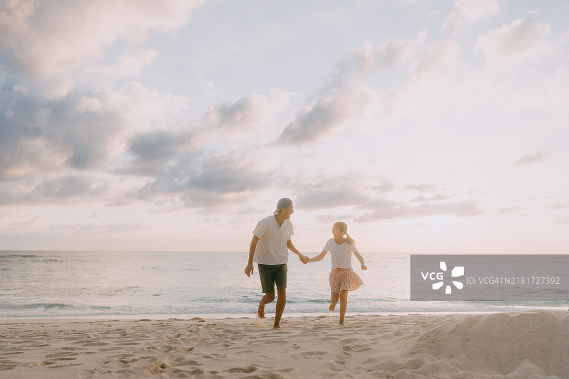 父亲和小女儿在日落时分的海滩上玩得很开心图片素材