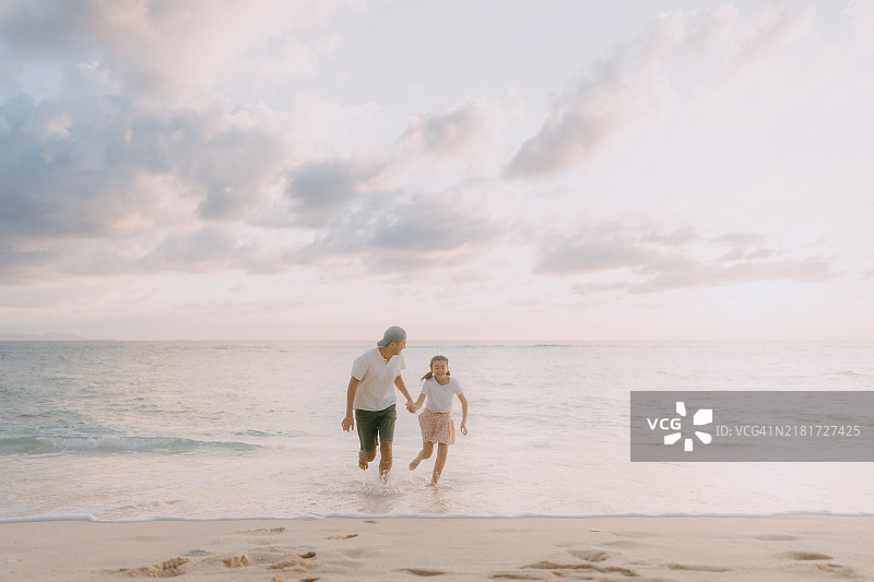 父亲和小女儿在日落时分的海滩上玩得很开心图片素材