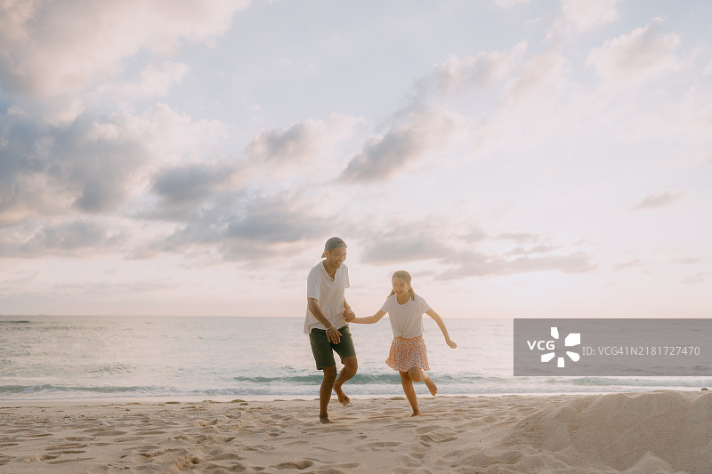 父亲和小女儿在日落时分的海滩上玩得很开心图片素材