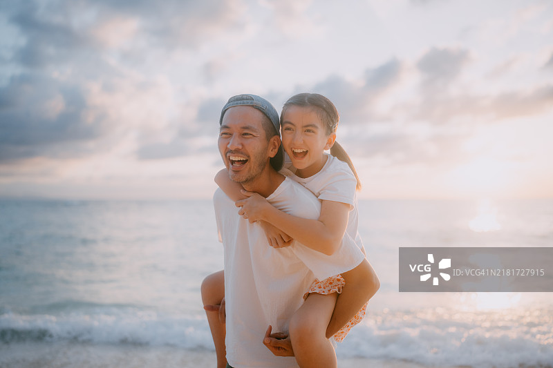 父亲和小女儿在日落时分的海滩上玩得很开心图片素材