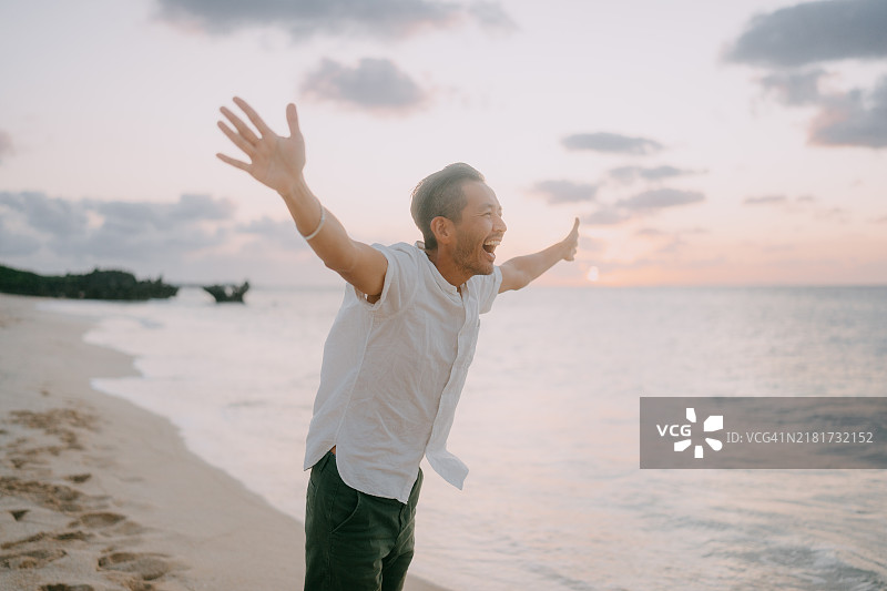 男人在日落时分的海滩上大喊图片素材