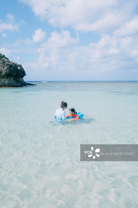 母亲和小女儿在清澈的热带水域中玩耍图片素材