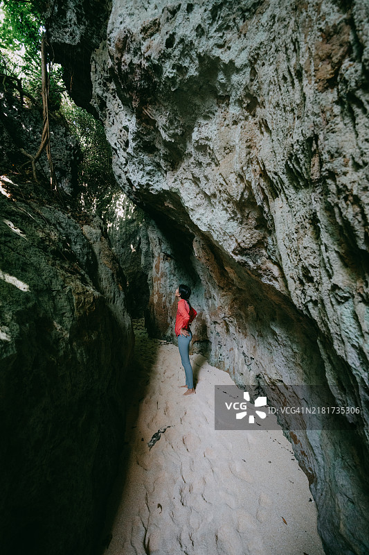 小女孩探索通往海滩的洞穴图片素材
